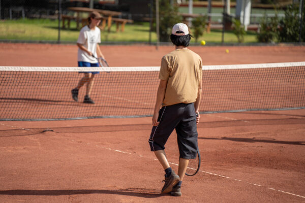 people playing tennis on a clay court at a local tennis club. young attractive people playing social tennis with friends and people watching enjoying being active and healthy in spring
