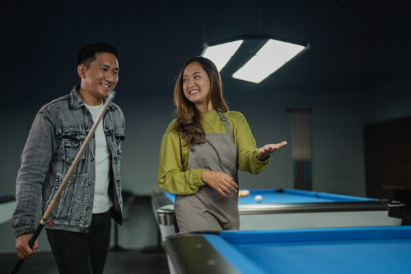 female pool table worker helps player arranging the balls with triangle rack